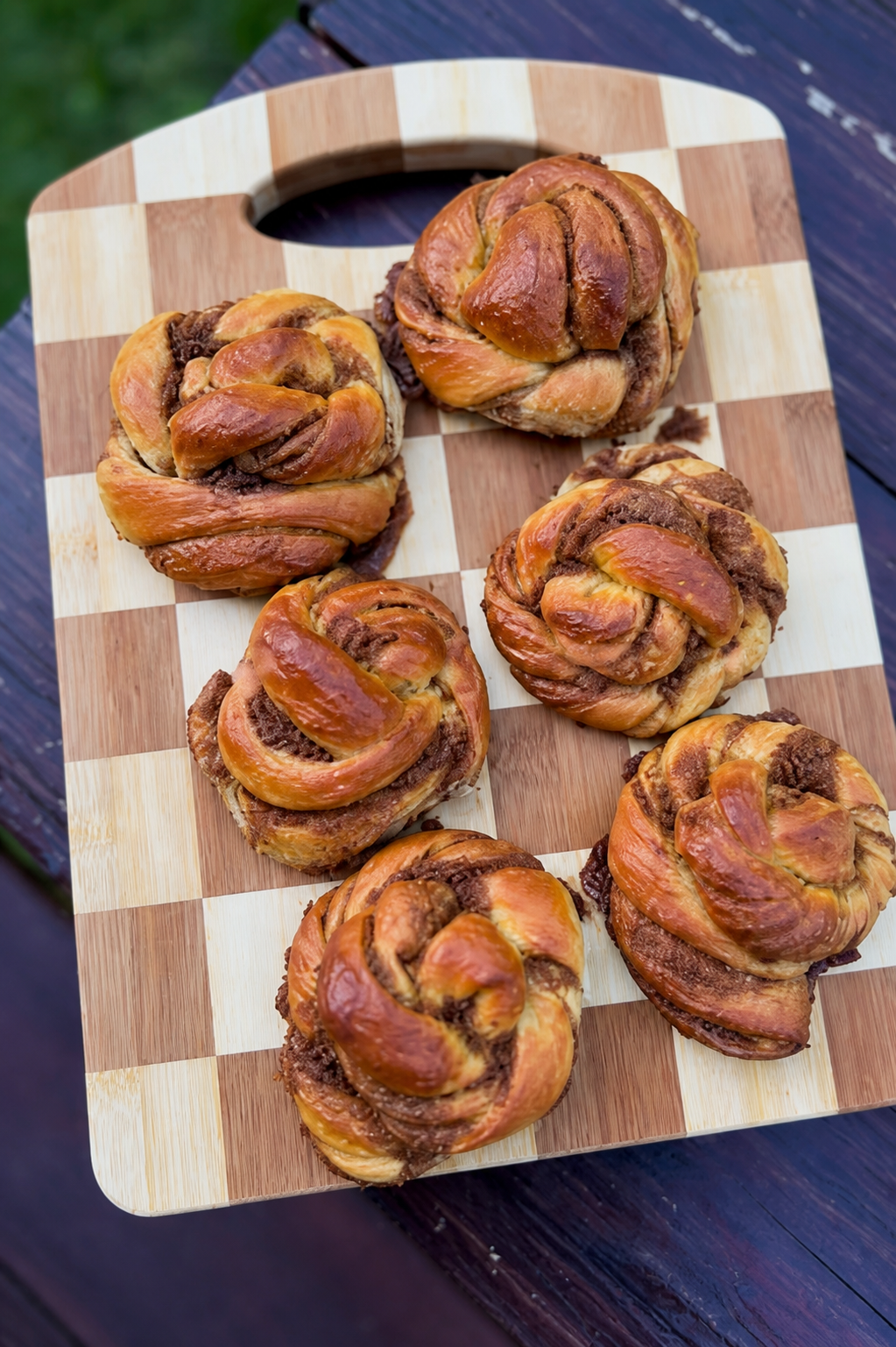 Hand-shaped cardamom buns on a wooden board
