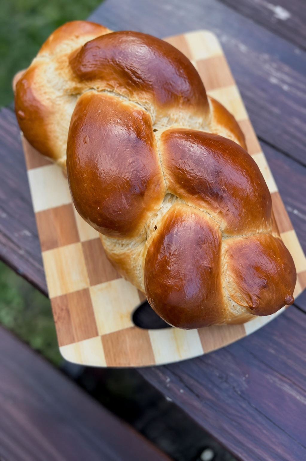 Glossy braided honey challah on a wooden board